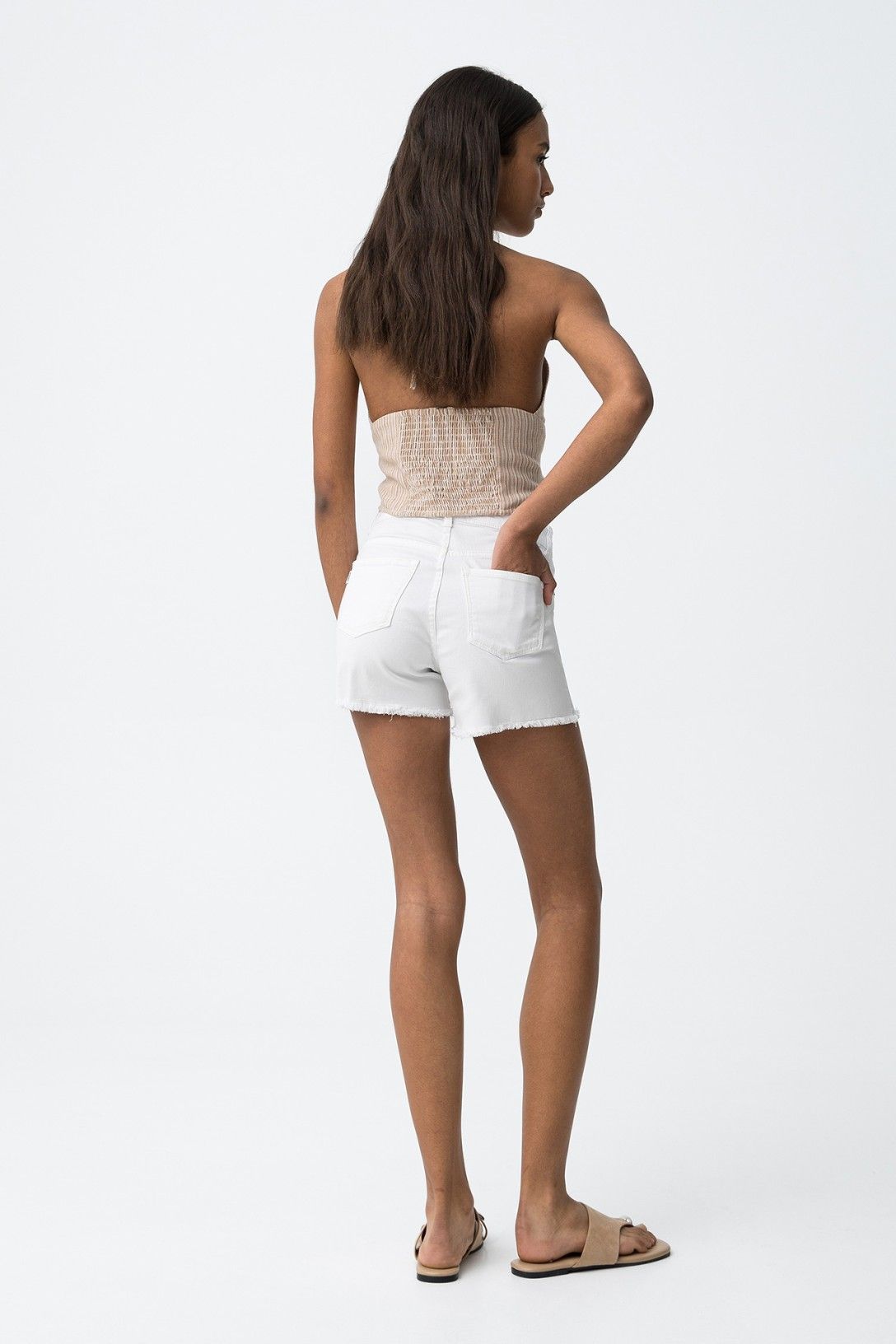 Short denim blanco con bajo deshilachado.