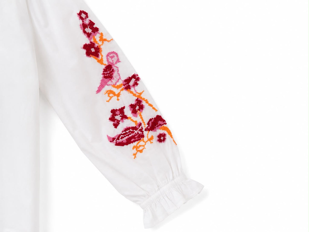 Camisa blanca con bordado en la manga en tonos rosa