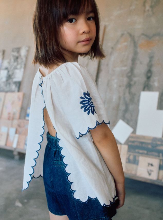 Blusa infantil con bordado y mangas onduladas.