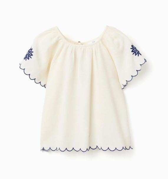 Blusa infantil con bordado y mangas onduladas.